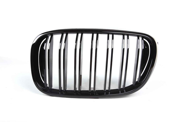 A shiny black car grille features vertical slats framed by an oval shape, set against a plain white background.