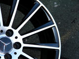 A black and silver alloy wheel with a star emblem is stationary on a rough, gray concrete surface.