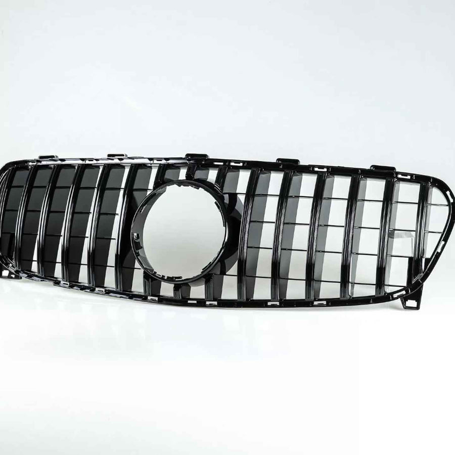 Car grille with vertical black slats and a circular central cutout, resting on a white surface, isolated against a plain white background.