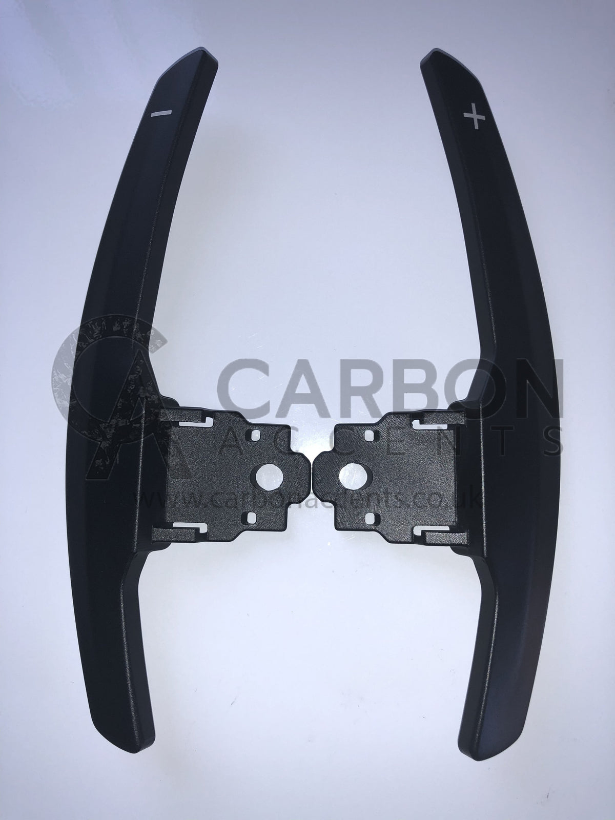 Paddle shifters with plus and minus symbols are displayed against a white background. The text reads, "CARBON ANCENTS www.carbonacents.co.uk."