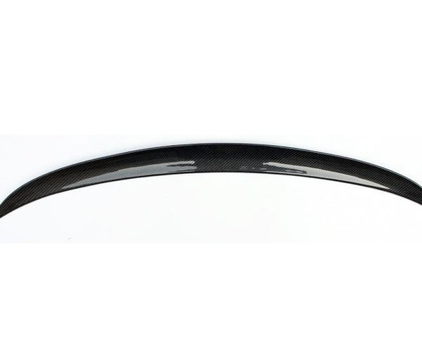 A glossy, black carbon fiber car spoiler arcs gracefully, displayed against a plain white background, highlighting its sleek and aerodynamic design.
