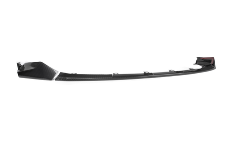 A black carbon fiber front splitter, slightly curved with aerodynamic design, rests isolated against a white background.