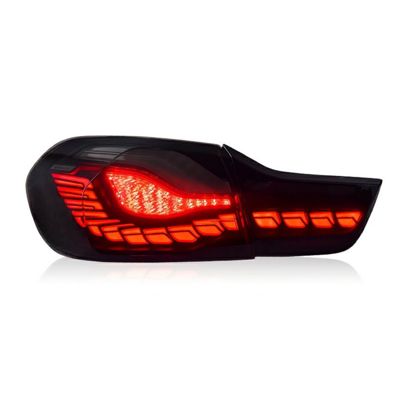 A car's rear light is illuminated with bright red segments in a sleek, modern design. It is set against a plain white background, highlighting the light's contours.