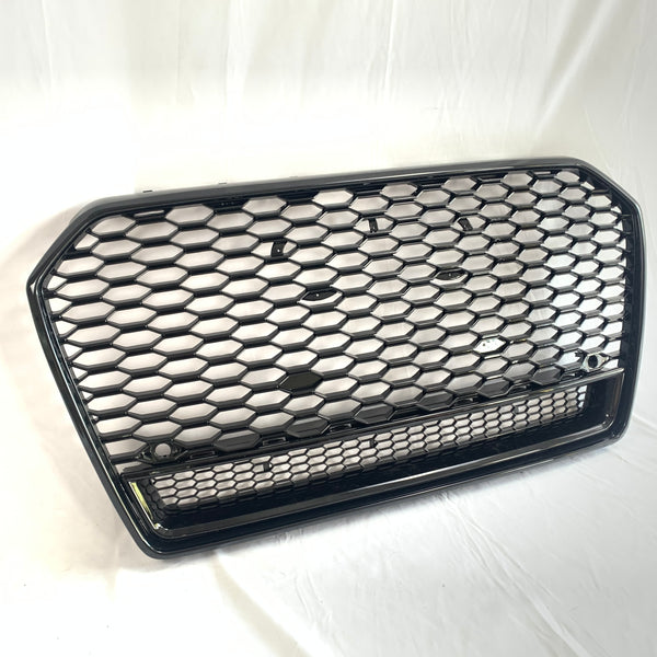 A black hexagonal mesh car grille rests against a white background. The grille features a honeycomb pattern and two round mounting points, suggesting automotive use.