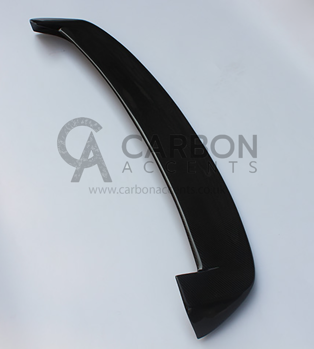 A black carbon fiber car spoiler rests on a white background. Text reads: "CARBON ACCENTS," with a website: "www.carbonaccents.co.uk" visible underneath.