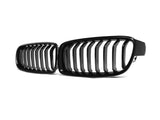 Black car grille with vertical slats, positioned angled toward each other, resting against a plain white background.