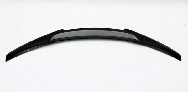 Curved black car spoiler rests horizontally on a plain white background, featuring a sleek, aerodynamic design with a central textured section, suggesting structural reinforcement or aesthetic detail.