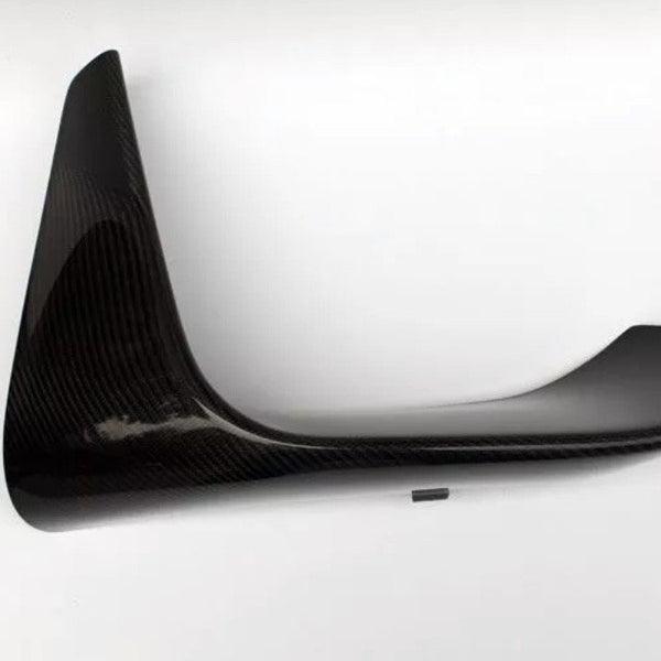 A black carbon fiber car spoiler is angled sideways against a plain white background, displaying its aerodynamic, curved shape and glossy finish.