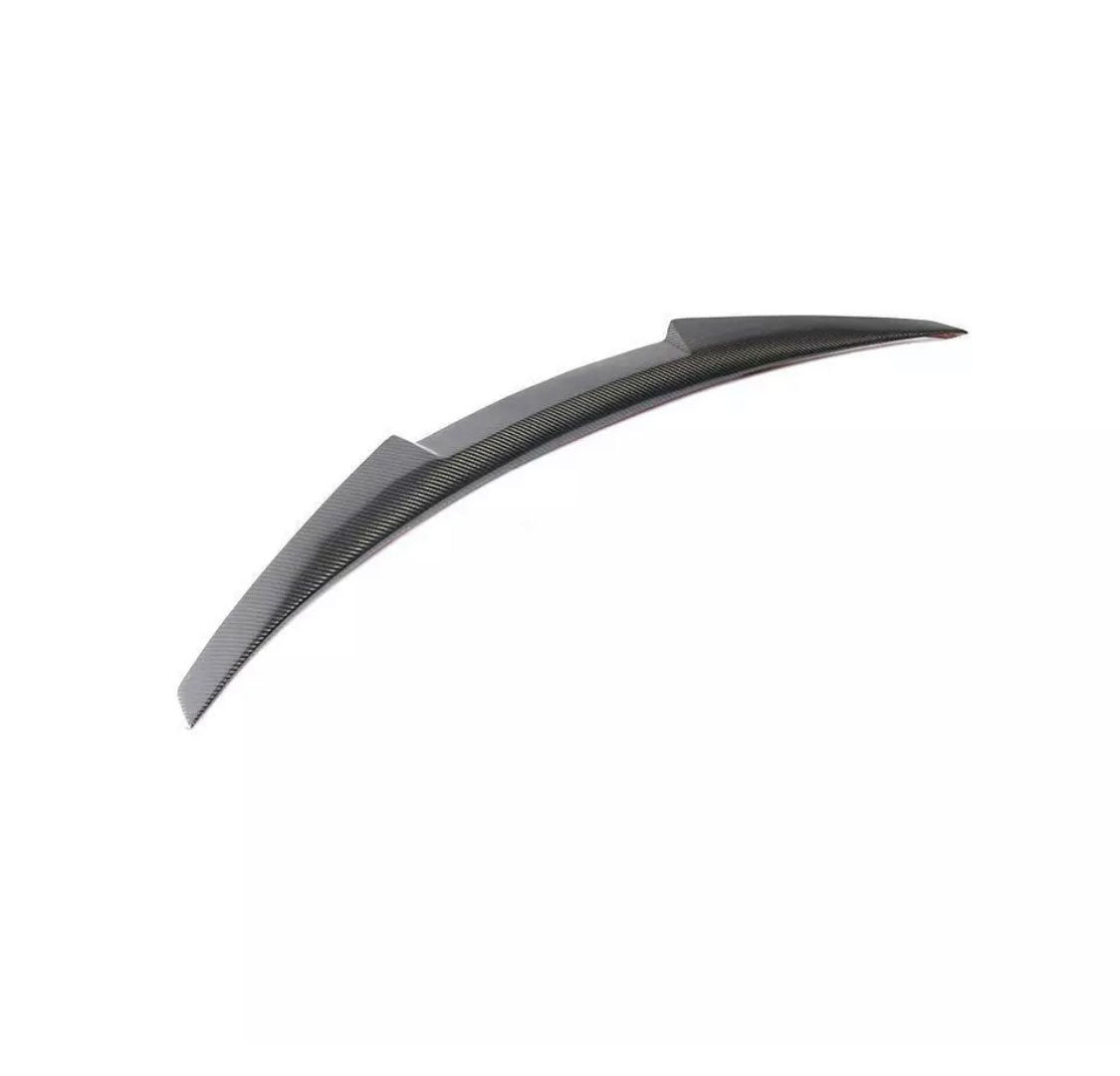 Curved carbon fiber car spoiler resting on a plain white background, designed to enhance vehicle aerodynamics.