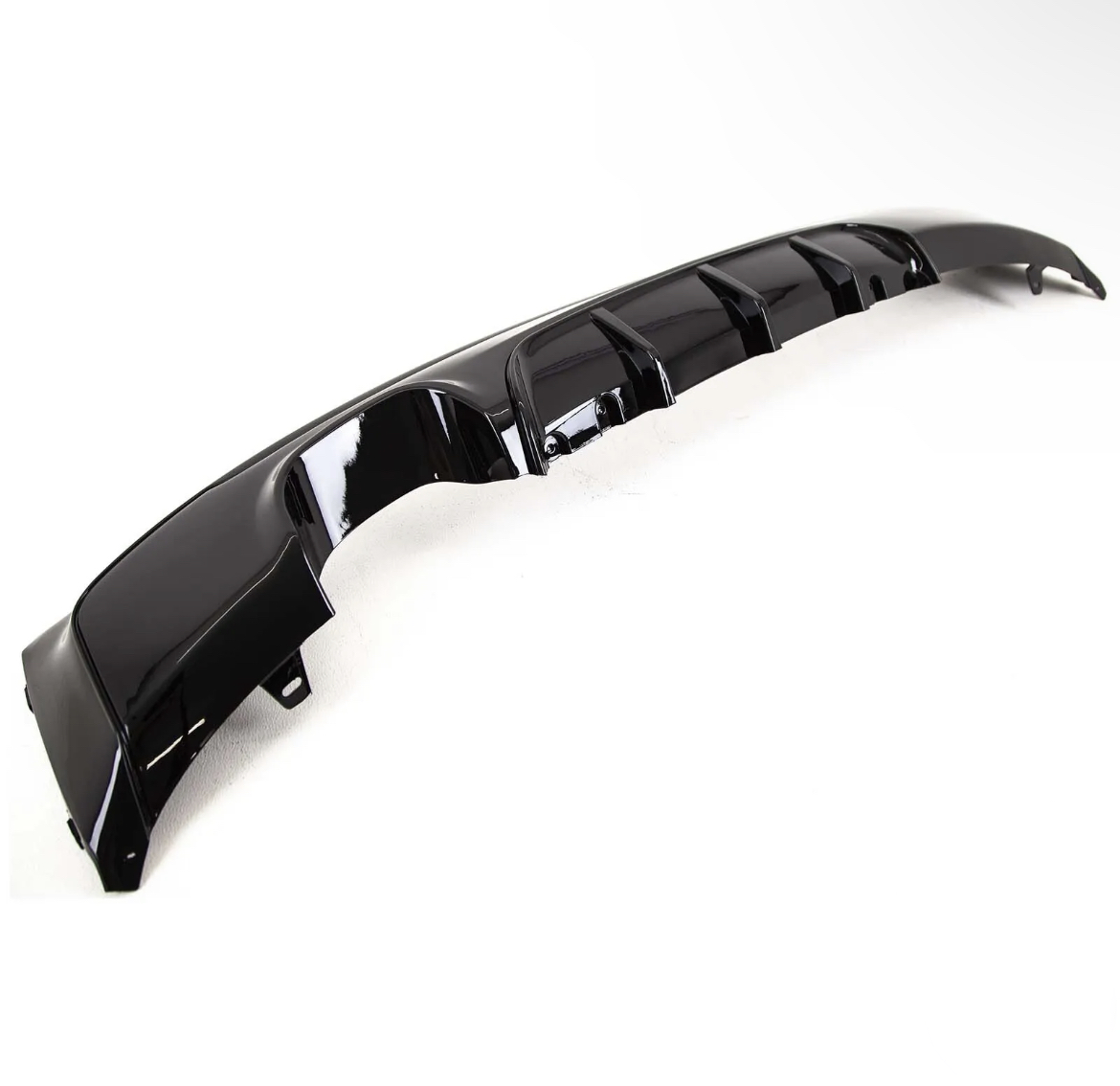A glossy black car bumper diffuser with fins lies on a plain white background, showcasing its aerodynamic contours and smooth finish.