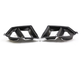 Carbon fiber car exhaust tips with dual openings, facing each other on a plain white background.