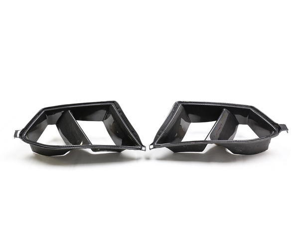 Carbon fiber car exhaust tips with dual openings, facing each other on a plain white background.