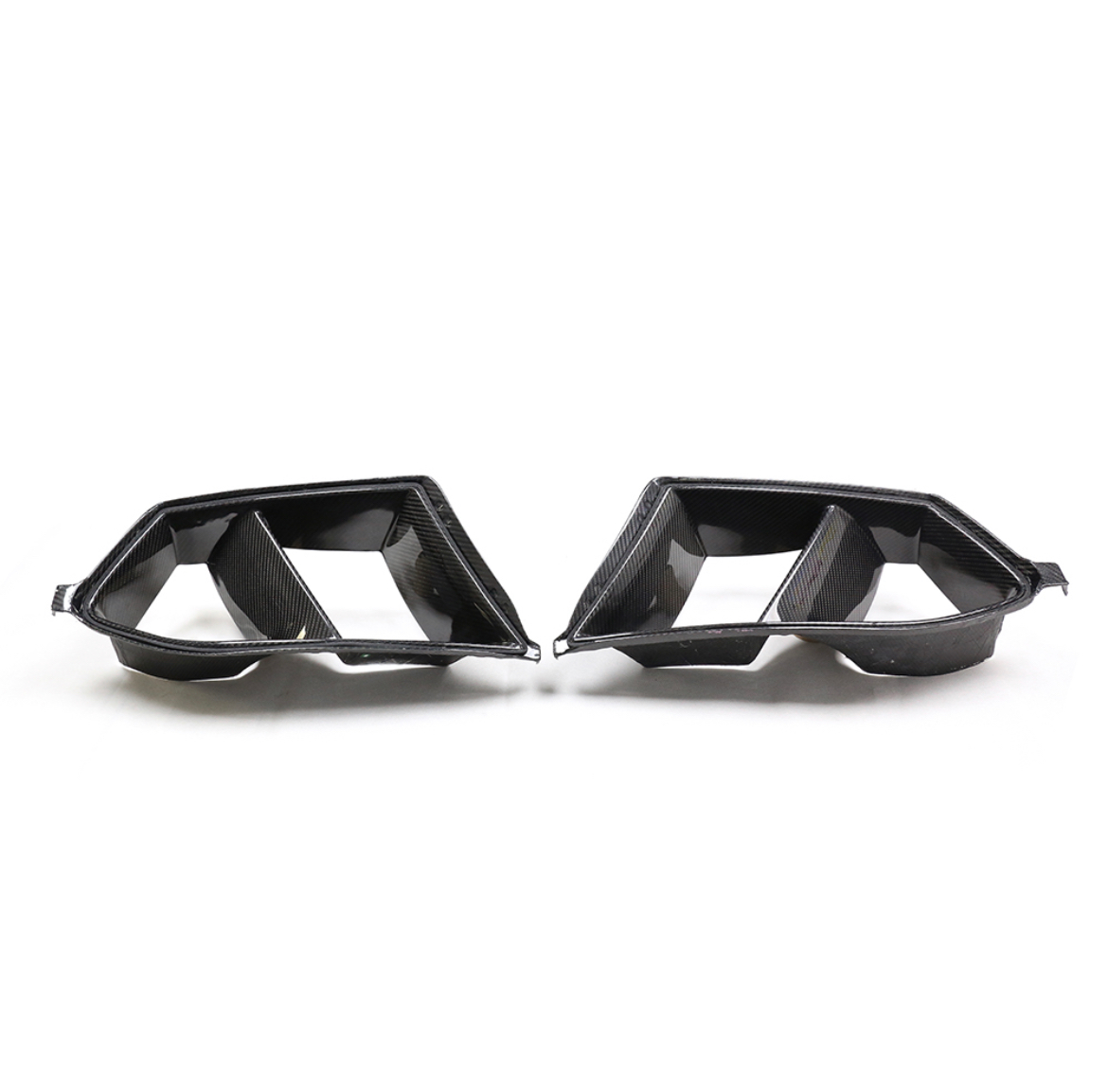Carbon fiber car exhaust tips with dual openings, facing each other on a plain white background.