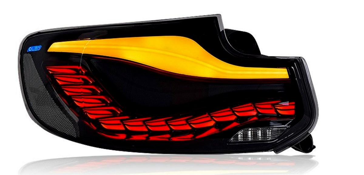 A modern car taillight featuring an illuminated dynamic design with red and yellow LED segments. The text "OLED" appears in the upper left corner on a reflective black surface.