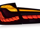 Car taillight illuminated, displaying bright red and amber segments. Positioned against a plain white background, the light consists of modern, geometric shapes, providing a sleek, stylish appearance.