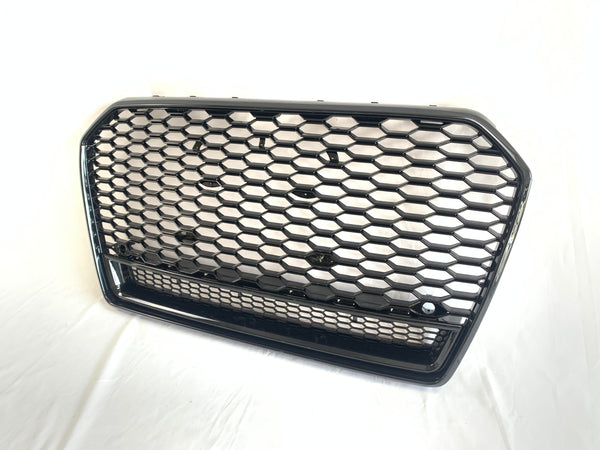 A hexagonal-patterned car grille, featuring a glossy black finish, rests on a white surface. The grille's design includes a prominent honeycomb structure, commonly used for automotive front ends.