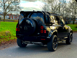 A black SUV is parked on a quiet road, with a grassy area and leafless trees surrounding it. Text 
