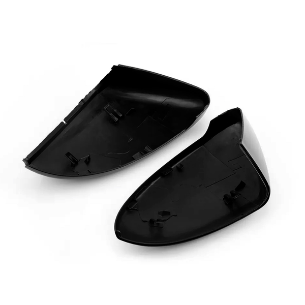 Two black plastic side mirror covers lie open, showing clips for attachment. They are positioned against a plain white background, highlighting their shape and design features.