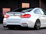 A sleek white BMW M4 with illuminated taillights sits stationary on a smooth asphalt surface, surrounded by a dimly lit industrial backdrop, featuring a partially visible building.