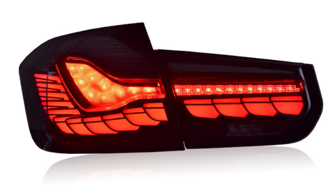 A sleek, modern car taillight, illuminated in bright red with intricate patterns, set against a plain white background.