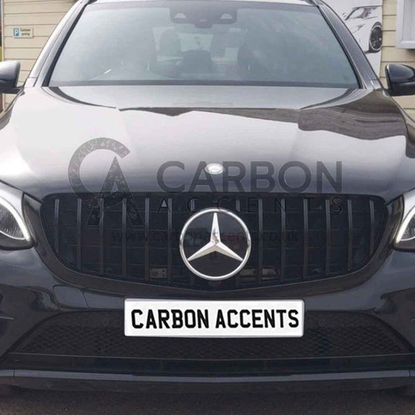 A black Mercedes-Benz car is parked outside a beige building, displaying the text "CARBON ACCENTS" on a white license plate. A small sign indicates "Customer parking" nearby.