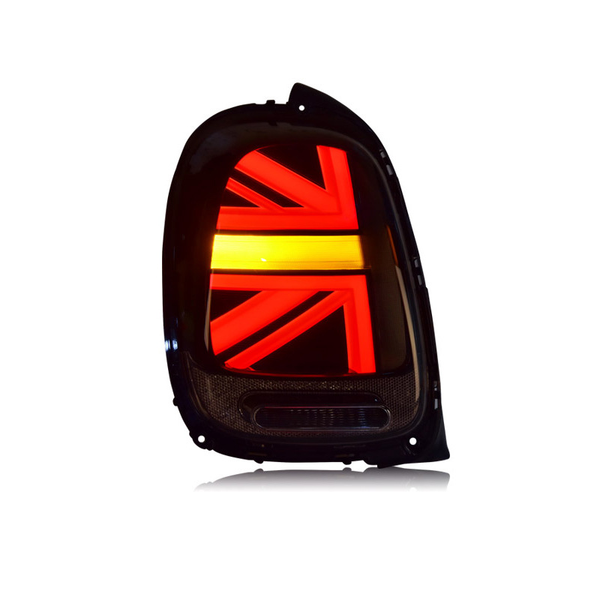 A car taillight illuminated in a Union Jack pattern emits red and yellow light within a black casing against a white backdrop.