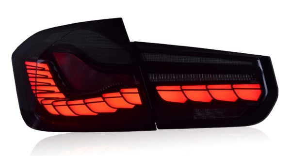 A sleek car taillight is illuminated in bright red, showcasing its angular design, isolated against a plain white background.
