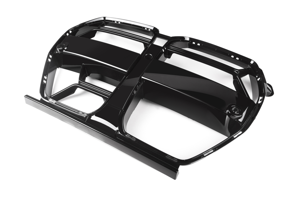 A black, glossy, plastic car grille lies on a white background. It features multiple elongated openings and a symmetrical design, designed for automotive airflow and aesthetic enhancement.