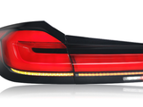 A sleek, modern car taillight with red, black, and amber segments, set against a white background, displaying sharp geometric lines and reflective surfaces.