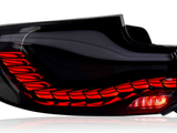 A car taillight glows brightly, illuminating red LED patterns within a sleek, modern black housing. The word 