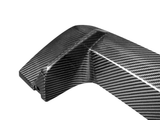 A sleek, carbon fiber object with a shiny, textured surface, likely a vehicle part, against a plain white background.