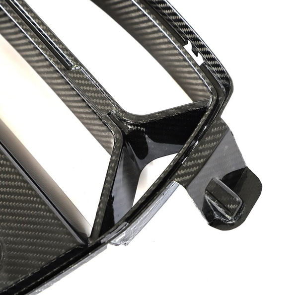 Carbon fiber car grille, angular with a glossy finish, resting against a plain white background, showing intricate weave patterns and structural design details.