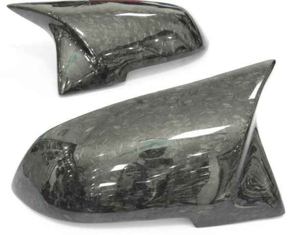 Two glossy carbon fiber car mirror covers lay angled on a white background, showcasing a sleek, modern design with a marbled pattern.