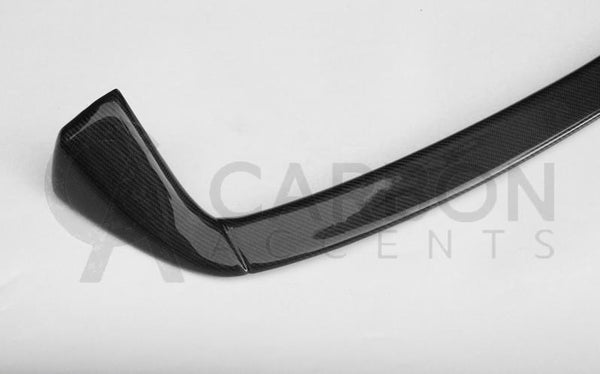 A carbon fiber car spoiler lies on a plain surface. The text "CARBON ACCENTS" is faintly visible across the image.