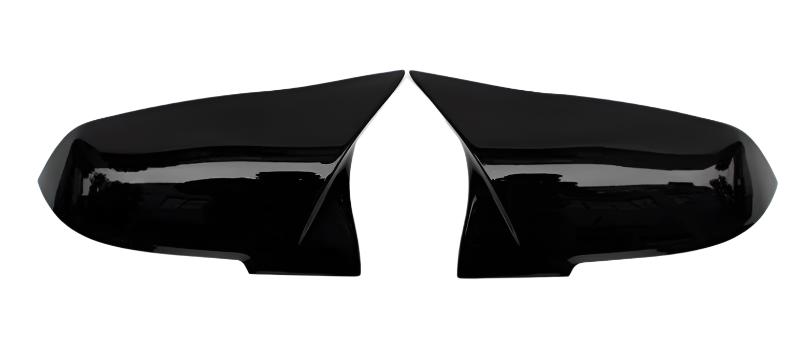 Two glossy black side mirror covers lie adjacent, separated, facing each other against a plain white background.
