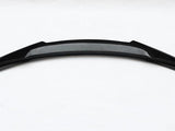 A curved black car spoiler, with a carbon fiber texture in the center, lies on a plain white background.