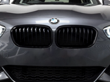 Car grille with vertical slats, featuring a BMW logo above, is prominently displayed on a dark gray vehicle in a well-lit indoor setting.