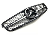 A black car grille features a central silver emblem with three pointed stars, bordered by a mesh pattern against a plain white background.