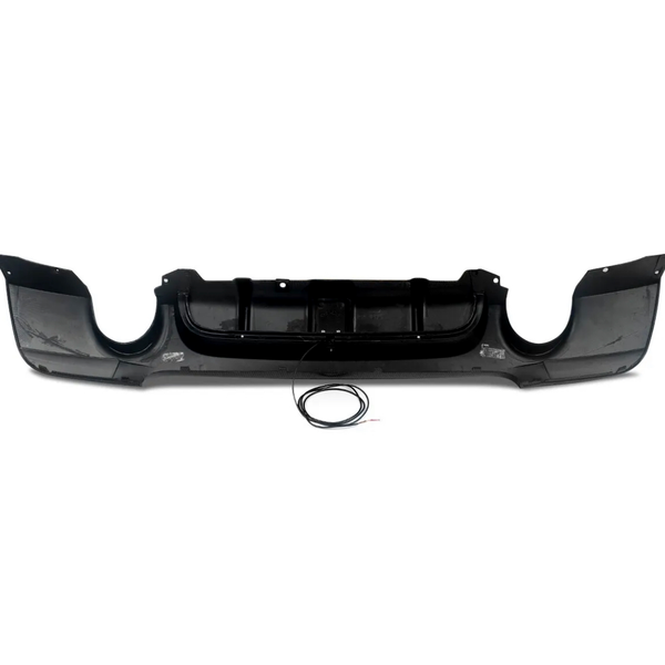 Black car bumper with aerodynamic design lying on a white background. A circular cable with exposed ends rests in front of the bumper.