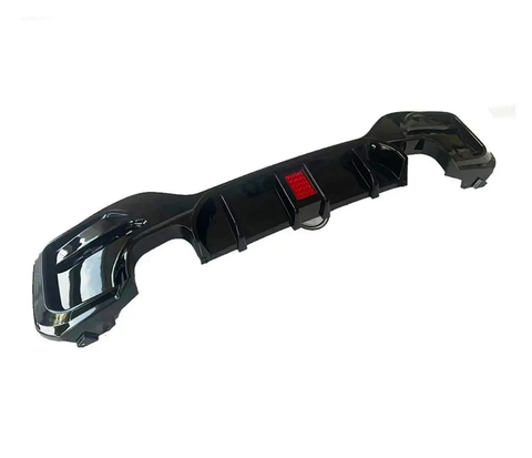A sleek black car bumper diffuser includes an integrated red reflector, designed for aerodynamic enhancement, shown isolated on a plain white background.