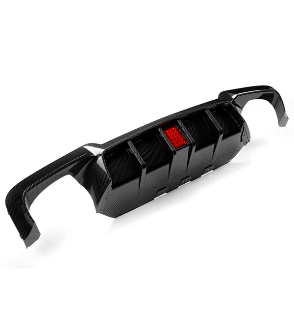 A carbon fiber car diffuser with a central red reflector. It features fins for aerodynamic purposes and is set against a plain white background, highlighting its sleek design.