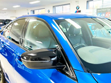 A shiny blue car is parked in a well-lit showroom, surrounded by other vehicles. Visible text includes “Your Next Car” and “MotoNovo,” indicating a promotional setting.