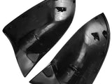 Two black, glossy, shark-fin shaped objects lie side by side, showcasing internal clips and connectors. They appear to be vehicle parts, possibly mirror covers, set against a plain white background.