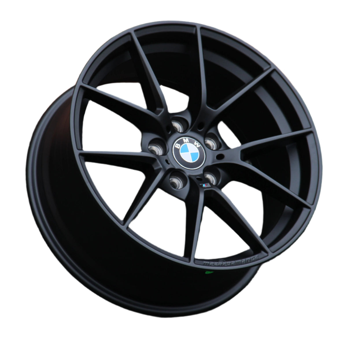 A black BMW alloy wheel with a multi-spoke design is positioned against a white background. The BMW logo is centered, surrounded by lug nut holes. "M PERFORMANCE" text is embossed on the rim.