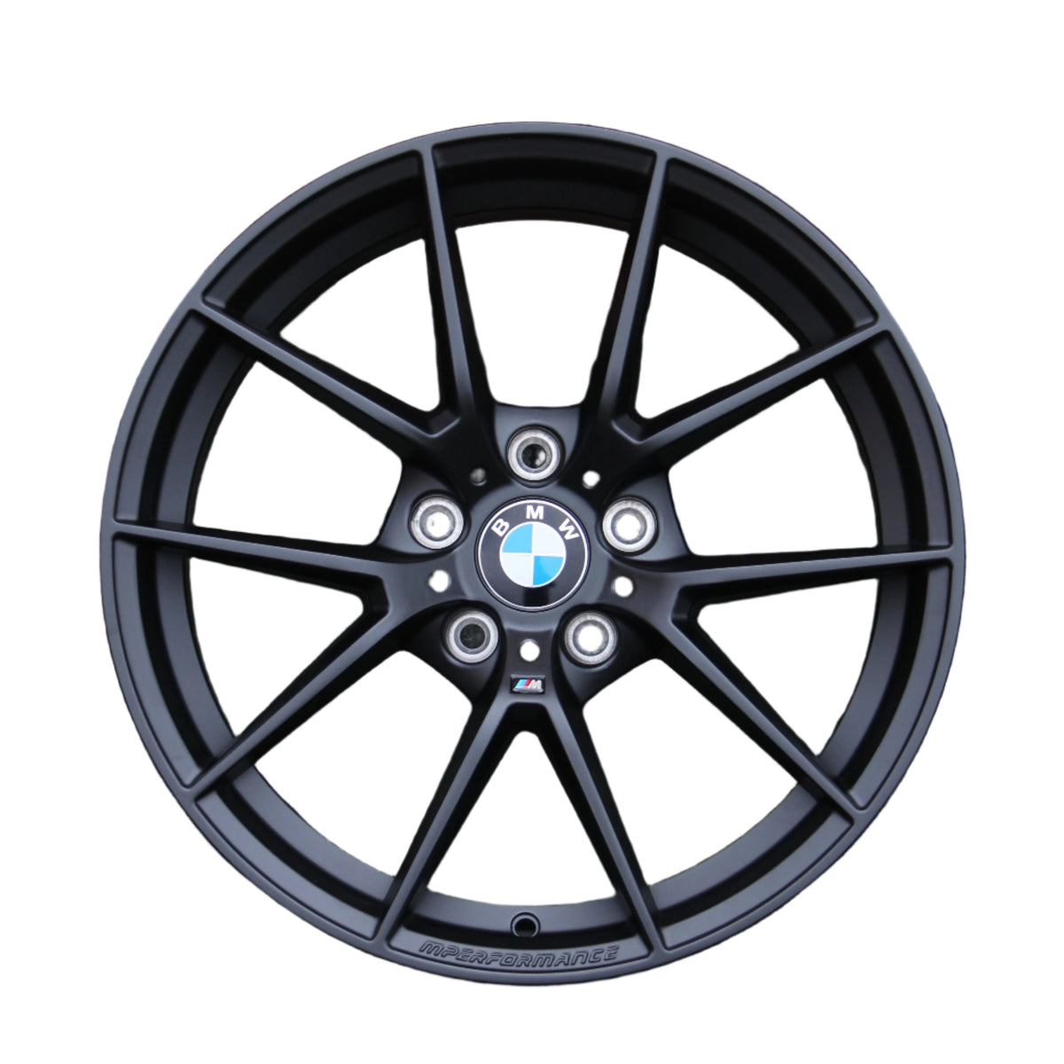 A black BMW alloy wheel features a ten-spoke design with the BMW logo at the center. "M PERFORMANCE" is embossed on the rim, set against a plain white background.
