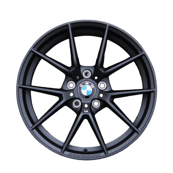 A black BMW alloy wheel features a ten-spoke design with the BMW logo at the center. "M PERFORMANCE" is embossed on the rim, set against a plain white background.