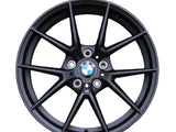 A black alloy wheel with a BMW logo at the center, featuring a multi-spoke design. Text includes 