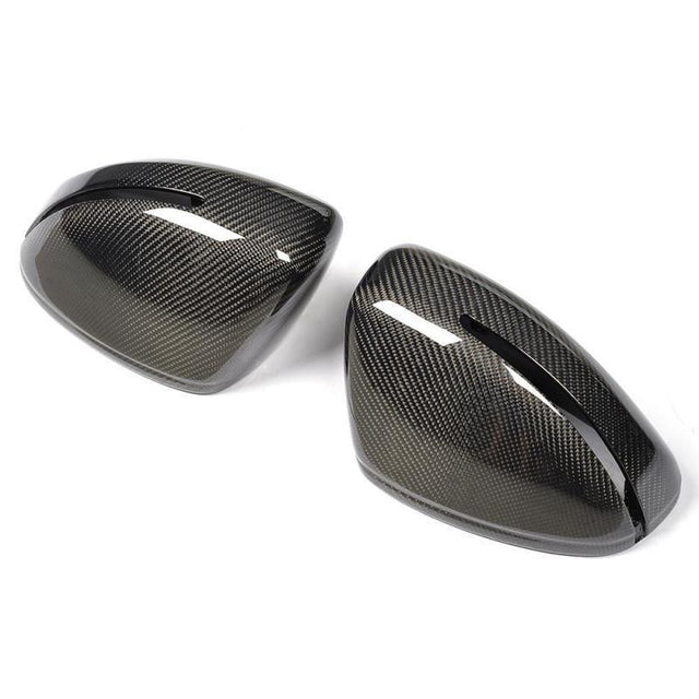 Two black carbon fiber car mirror covers with a sleek, glossy finish, positioned side by side, against a plain white background.