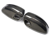 Two carbon fiber car mirror covers are positioned side by side on a plain white background, showcasing a sleek, glossy finish and intricate weave pattern typical of carbon fiber material.