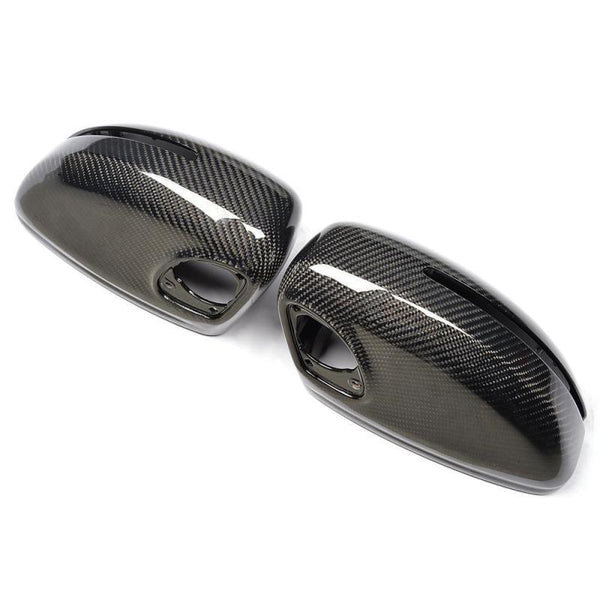 Two carbon fiber car mirror covers are positioned side by side on a plain white background, showcasing a sleek, glossy finish and intricate weave pattern typical of carbon fiber material.